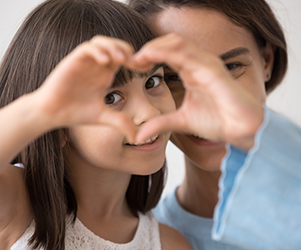 Little girl making heart shape with mom